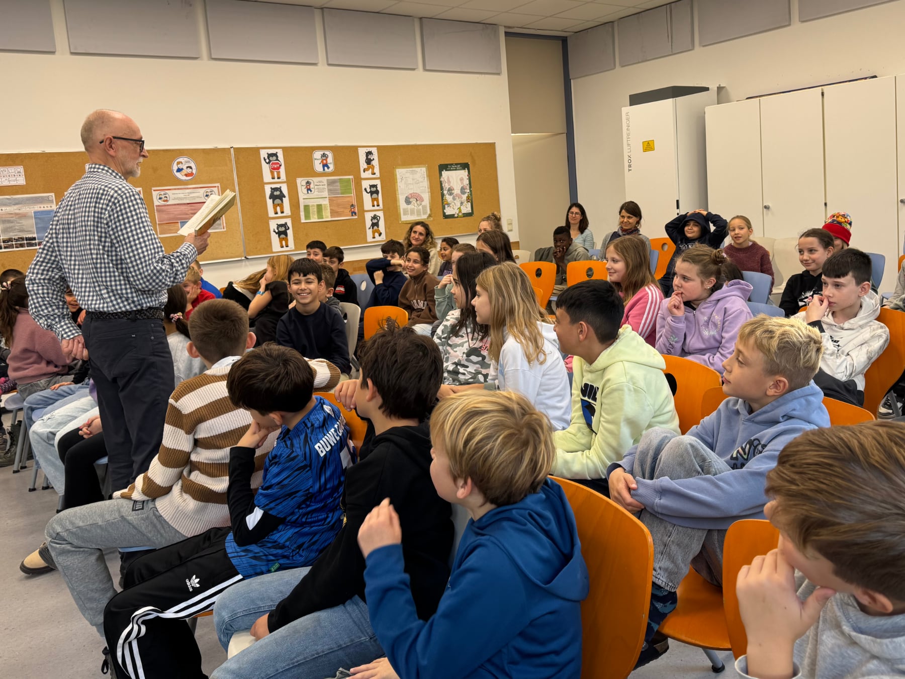 Herr Stohner leist aus dem Buch "Ella" in mitten der sitzenden Kinder vor.