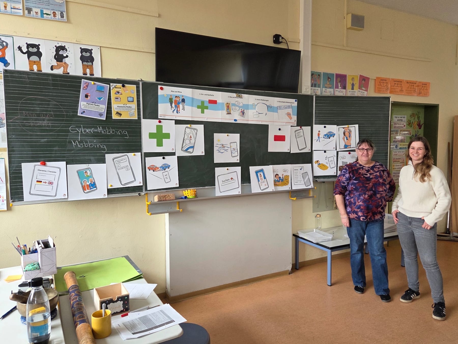 Die Schulsozialarbeiterinnen erklären vor der Tafel die Aufgaben.