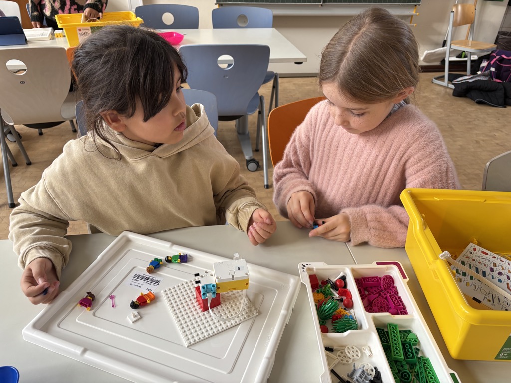 Zwei Kinder bauen an einem Robotik-Objekt.