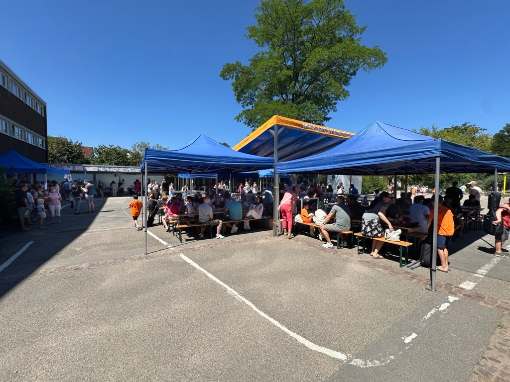 Gäste des Festes unter den Pavillons im Schulhof im Schatten